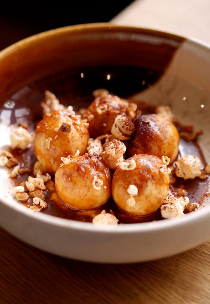 A mouthwatering gourmet dessert featuring small pastry balls in a rich sauce.